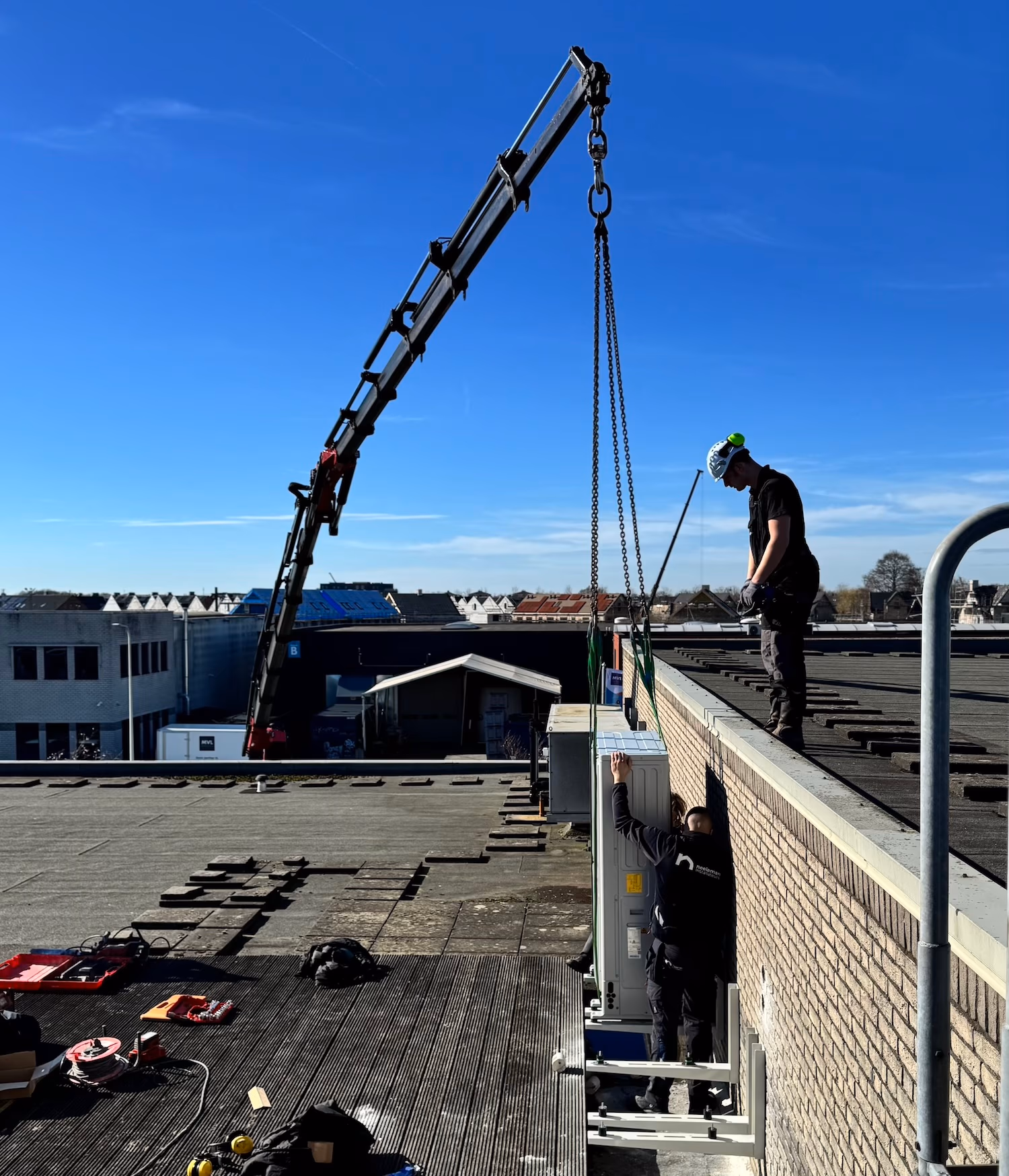 Foto van Neeleman monteurs die de Nefit-Bosch buitenunits op het dak heisen
